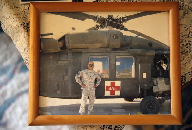 ADVANCE FOR USE SUNDAY, AUG. 16, 2015 AND THEREAFTER - This March 17, 2015 photo shows a photgraph of now-retired U.S. Army Sgt. 1st Class Marshall Powell standing with a U.S. Army MEDEVAC helicopter in Iraq during his last tour to the country, at Powell's brother's house in Crescent, Okla. Powell, who served as a military nurse in Iraq and Afghanistan, was deeply haunted by his experiences, and nearly lost his own internal war with depression before finding meaningful help. (AP Photo/Brennan Linsley)