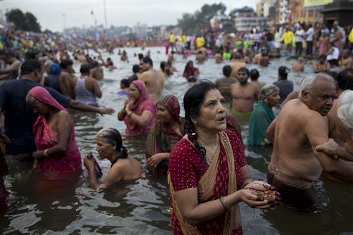 An Indian woman devotee performs rituals as others take holy dips in the Godavari River during Kumbh Mela, or Pitcher Festival, in Nasik, India, Wednesday, Aug. 26, 2015. AP