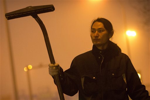Chinese artist Wang Renzheng demonstrates the use of his industrial shop-vac alongside a highway in Beijing, Tuesday, Dec. 1, 2015. Wang spent 4 hours per day for 100 days vacuuming the Beijing air with an industrial shop-vac, then baked the accumulated dust and pollutants into a brick. (AP Photo/Mark Schiefelbein)
