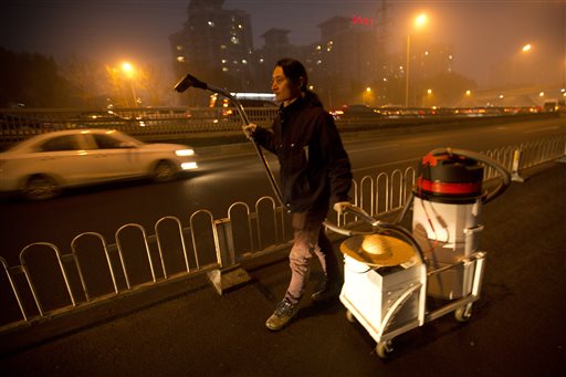 Chinese artist Wang Renzheng walks along a highway as he demonstrates the use of his industrial shop-vac in Beijing, Tuesday, Dec. 1, 2015. Wang spent 4 hours per day for 100 days vacuuming the Beijing air with an industrial shop-vac, then baked the accumulated dust and pollutants into a brick. (AP Photo/Mark Schiefelbein)