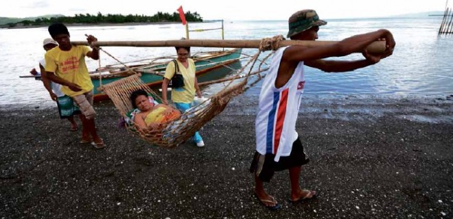 BYWATER AND BY LAND Porters on the island village of Old Caaluan carry a pregnant woman in a hammock to a boat that will ferry her to the mainland, where a “habal-habal” is waiting to take her to a hospital in Tinambac. PHOTO COURTESY OF ZUELLIG FAMILY FOUNDATION