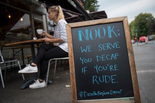 The Nook Neighbourhood Coffee shop advertises its coffee with a contentious phrase written on a chalk A-board outside the premises in Stockport, north west England on September 13, 2016. The daily grind of London commuting is being brightened by a collection of black marker pens and white boards -- giving city dwellers a welcome boost as they travel through the metropolis. The messages sometimes use humour rather than straightforward positive PR, such as one board outside a cafe in Stockport: "Come in and try the worst porridge that one woman on TripAdvisor had in her life". / AFP PHOTO / OLI SCARFF / TO GO WITH AFP STORY BY EDOUARD GUIHAIRE