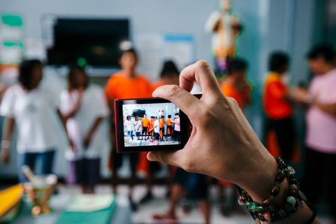 Donor taking photo of children performing