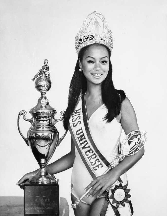 Gloria Diaz, Miss Universe 1969, displays some of her prizes.  Although Miss Universe no longer receives a sceptor or a trophy, she does receive prizes from sponsors that range from Clairol to Mikimoto Pearls to Maurice Lacroix and Hoya Crystal.