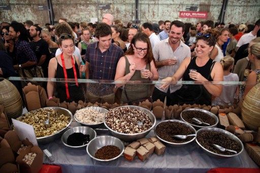 This photo taken on January 28, 2017 shows customers looking at different kinds of insects at a stall in Sydney. Roasted cockroach, honey-flavoured ants, mealworm and chocolate coated popcorn are now available to try and buy -- and while the cuisine remains a novelty, there are signs it is growing in popularity. AFP PHOTO