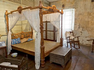 A reproduction Ah Tay bed with its “kalabasa” squash design lords over the bedroom. The new bed does not dispel the air of things past. Photo by Needs and Solutions