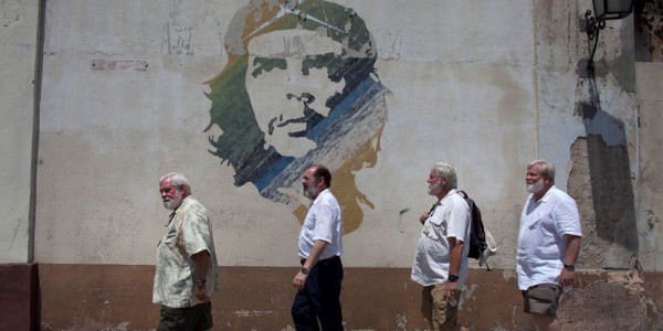 Men who look like the late American writer Ernest Hemingway pose for photos as they walk past a mural of Cuban revolutionary hero Ernesto "Che" Guevara after visiting a rum museum in Havana, Cuba, Saturday, June 22, 2013. AP
