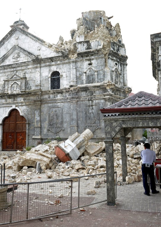 A guard stands beside the ruins of Basilica Minore del Santo Nino bell tower following a 7.1-magnitude quake in Cebu. AFP