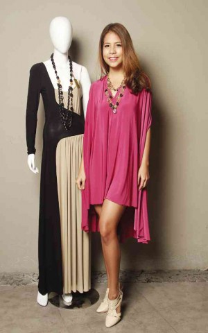 MIA ARCENAS in a jersey cape dress beside amannequin wearing a contrasting jersey draped gown