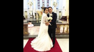 EM, wearing amodern Victorian-inspired lace wedding gown by Veluz Reyes, andMark during their Catholic wedding at the Church of St. Teresa in Singapore