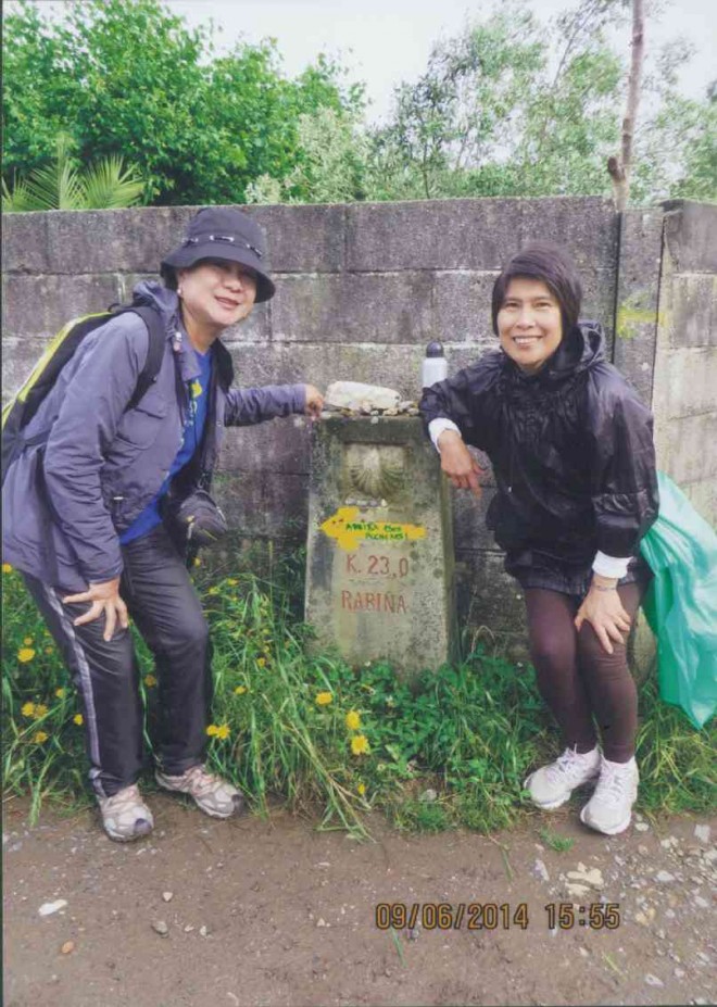 THE AUTHOR andMaris Gavino at one of themarkers (mojon) that states that we have 23 km to go to reach Santiago de Compostela