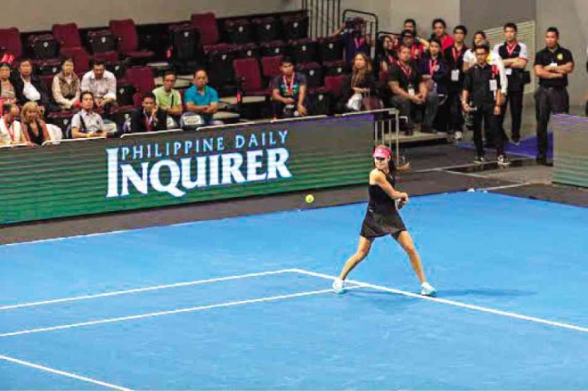 ANA IVANOVIC hits a backhand just as the INQUIRER logo comes out at courtside.