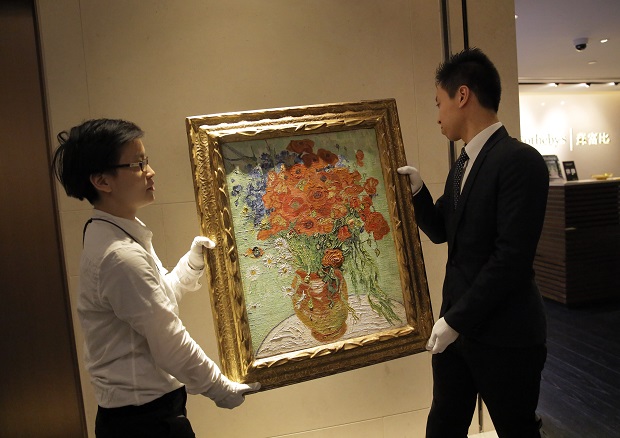 Employees of Sotheby carry the painting of Vincent van Gogh's " Vase with Daisies and Poppies " after a ceremony at the Sotheby's auction house in Hong Kong Saturday, Dec. 6, 2014. Sotheby's New York Impressionist and Modern Art Evening Sale on November 4 sold the painting to Chinese Movie Mogul Wang Zhongjun and set a new record for any still life by the artist at US$61.76 million. AP
