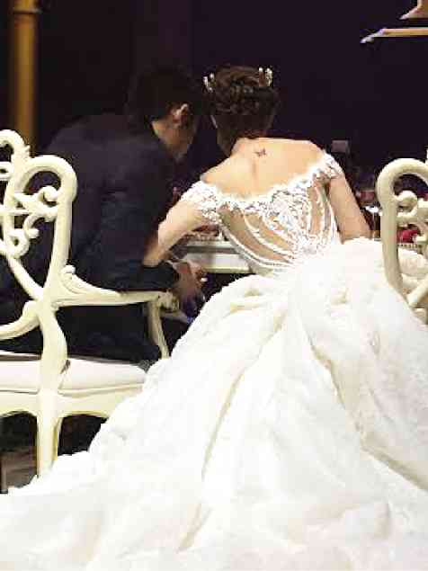 The delicate traceries on the bride’s gown by Michael Cinco call tomind the curlicues on their elaborately carved chairs.