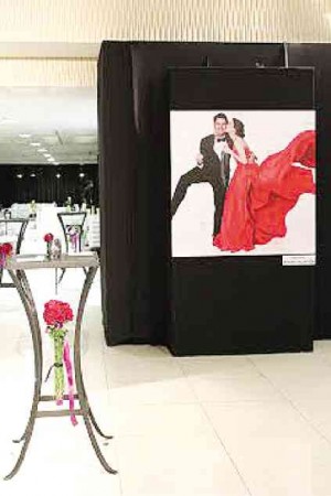 THE COCKTAIL area was decorated with blown-up photos of the couple. Underneath the cocktail tables were tightly bound bunches of roses.