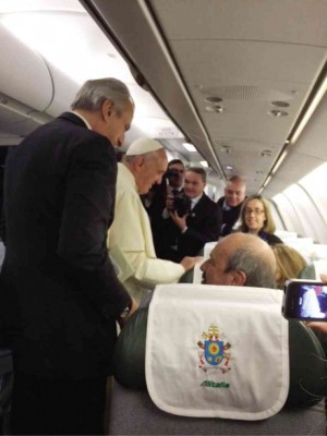 POPE Francis greets journalists at the start of his journey aboard Alitalia. Note the headrest with papal coat of arms.
