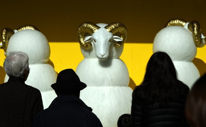 Pedestrians look at next year's "Year of the Sheep", part of a display window at a department store, in the Ginza shopping district of central Tokyo on December 26, 2014. Japan's factory output and inflation rate slowed in November, official data showed on December 26, dealing a fresh challenge for Tokyo's bid re-boot the economy, just days after pro-business Prime Minister Shinzo Abe was re-elected following a snap election.  AFP