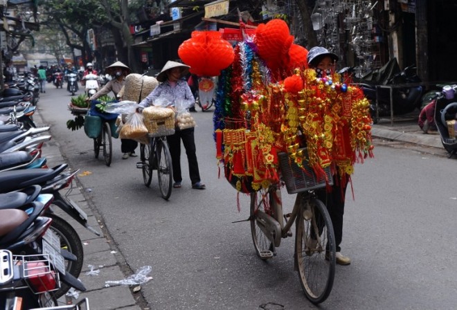 Street vendors walk their bicycles loaded with goods for sale along a street in the old quarter of Hanoi as Vietnamese prepare to celebrate Tet, or Vietnamese Lunar New Year, in Hanoi on February 12, 2015. AFP 