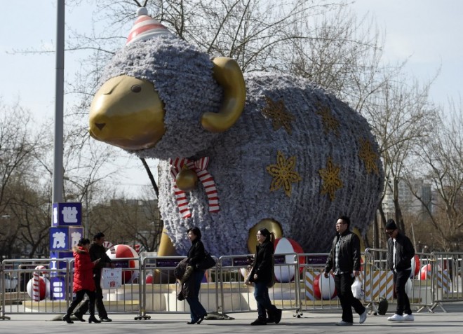 People walk past a giant sheep outside a shopping mall as part of decorations for the upcoming Lunar New Year in Beijing on February 16, 2015. China's coming lunar new year has stirred a debate over which zodiac creature - sheep or goat - is the correct one -- but Chinese folklorists dismiss the fixation on animals as missing the point. AFP 
