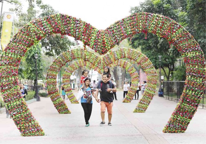 HEART OF HEARTS  A family walks past an installation of a series of big hearts at Rizal Park in Manila on the eve of Valentine’s Day, when lovers are drawn to the historical urban park, a favorite leisure spot for lovers and other strangers. JOAN BONDOC 