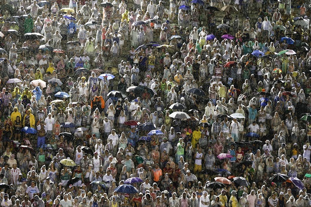 Spectators stand in plastic rain slickers and, or with umbrellas as they watch the Viradouro samba school file past in the Carnival parade at the Sambadrome in Rio de Janeiro, Brazil, Sunday, Feb. 15, 2015. The skies opened up Sunday evening, about an hour ahead of the start of the all-night-long extravaganza, drenching revelers and flooding streets near the Sambadrome. (AP Photo/Felipe Dana)