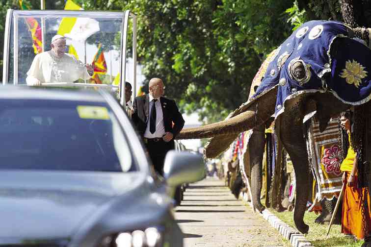 ELEPHANT extends its trunk as if to greet Pope Francis, who can only beam in delight at the unique welcome provided him by Sri Lanka on Jan. 13. Meanwhile papal bodyguard looks anxiously. AP