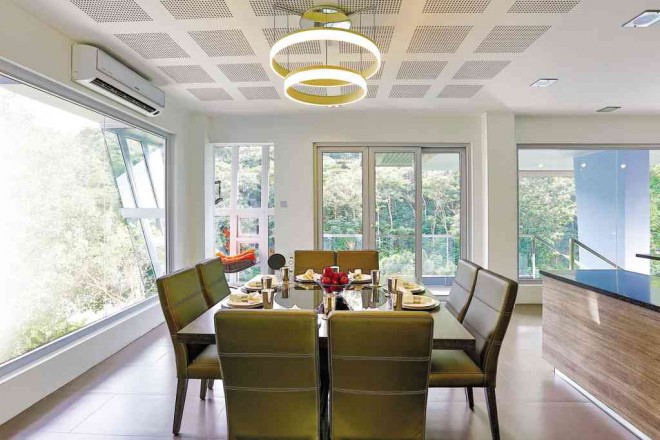 PERFORATED ceiling ensures good acoustics. Doublering LED chandelier over the dining table in dark wenge and leather chairs, all by Padua.