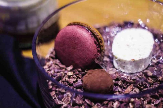 A TRIO of sweets: A macaron of Malagos chocolate and bignay (a nativewild berry); a Malagos chocolate truffle filled with dulce de leche and bignay compote; and a truffle polvoron rest on roasted cacoa bean pieces