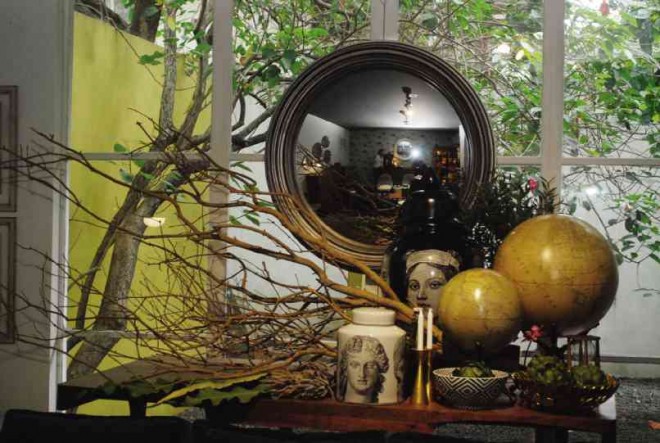 BRANCHES lend a rustic touch to the display of a mirror, globes and ceramic jars.