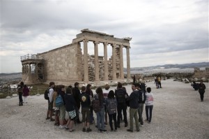 Tourists listen to a guide as they stand in front of the Erechtheion temple during a visit at the Acropolis hill in Athens, on Wednesday, April 15, 2015. AP