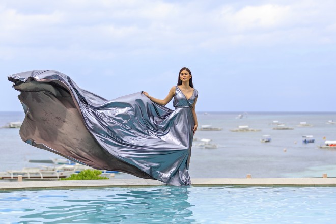 THE WIND sculpts the Eric de los Santos gown of Pia Alonzo Wurtzbach as she stands on the rim of the infinity pool of Amorita, her backdrop the expanse of Alona Beach and the clear summer sky of Bohol. 