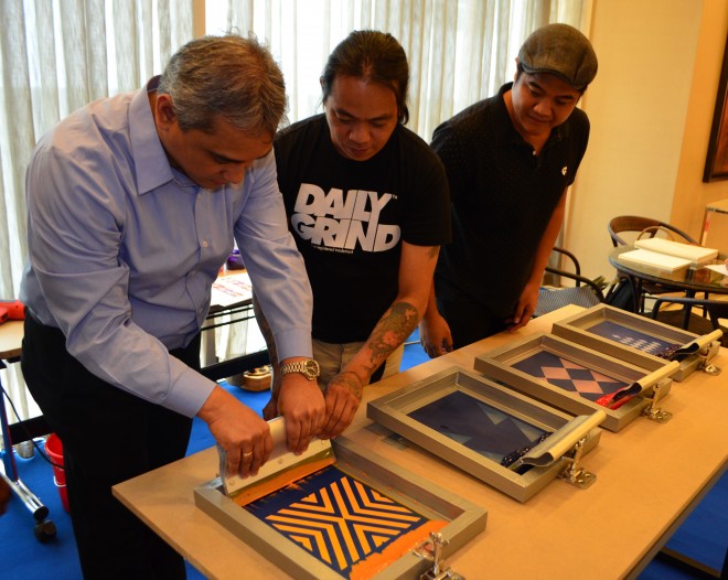 Avida Land president and CEO Chris Maglanoc tries the live silk screen art at Team Manila’s booth. CONTRIBUTED IMAGE