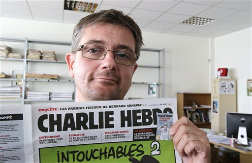 In this Sept.19, 2012 file photo, Stephane Charbonnier also known as Charb , the publishing director of the satyric weekly Charlie Hebdo, displays the front page of the newspaper as he poses for photographers in Paris. AP