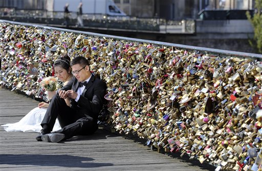 This Wednesday April 16, 2014 file photo shows a newly wed couple resting on the Pont des Arts in Paris, France.  AP