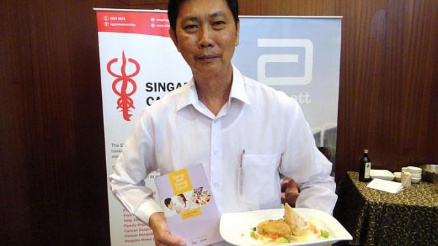 Ricky Chiu, 61, posing with the Singapore Cancer Society's booklet with tips to help cancer patients eat right, and a sample of a meal suited to a cancer patient. Chiu was diagnosed with throat cancer in 1997, but has since fully recovered. Photo from WAGGENER EDSTROM COMMUNICATIONS/The Straits Times/Asia News Network