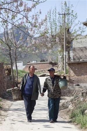 Jia Wenqi, left, and Jia Haixia walk along a lane in Yeli village. AP