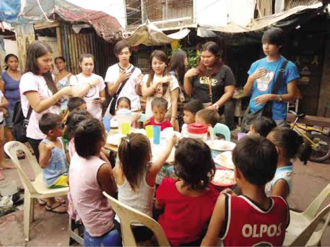STUDENT volunteers help in feeding and teaching catechism to impoverished children.