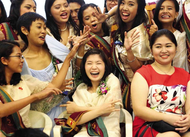  University of the Philippines student Tiffany Grace Uy (center) horses around with her classmates during the recognition rites at the Institute of Biology on Friday. The summa cum laude graduate, the daughter of doctors, will pursue medical studies in August because “a doctor makes me feel safe.” MARIANNE BERMUDEZ
