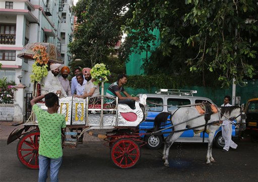 A man takes the picture of a group of Sikhs taking a pleasure ride on a horse drawn carriage popularly known as ‘victorias’ in Mumbai, India, Tuesday, June 9, 2015. The horse drawn carriages are one of city’s tourist attractions. AP