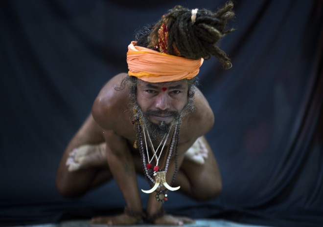 In this Friday, June 12, 2015 photo, an Indian Hindu holy man, illustrates the yoga pose Kakasana, or the crow pose in Gauhati, India. Sunday marks the first International Yoga Day, which the government of India Prime Minister Narendra Modi is marking with a massive outdoor New Delhi gathering. (AP Photo/Anupam Nath)