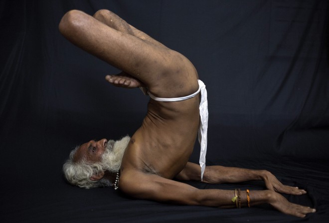 In this Friday, June 12, 2015 photo, an Indian Hindu holy man, illustrates the yoga pose, urdhva padmasana, a sort of half-headstand, where the yogi lies on his back and puts his crossed legs in the air, in Gauhati, India. Sunday marks the first International Yoga Day, which the government of India Prime Minister Narendra Modi is marking with a massive outdoor New Delhi gathering. (AP Photo/Anupam Nath)