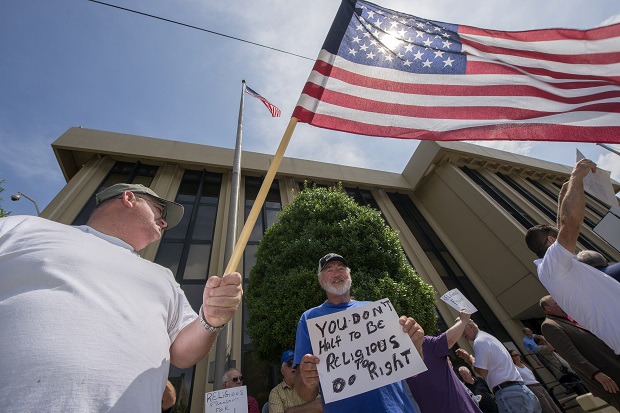 Tom Lowe, left, and James Perkins, with sign, show their support for Rowan County Clerk Kim Davis Monday, July 13, 2015, at the United States District Court for the Eastern District of Kentucky in Ashland, Ky. A federal judge is hearing arguments Monday about Davis, one of a hand full of local officials across the country who are refusing to issue any marriage licenses after the U.S. Supreme Court's ruling legalizing same-sex marriage. The U.S. Supreme Court decided June 26 states cannot prohibit issuing marriage licenses to same-sex couples, but Davis has refused citing her religious beliefs. (AP Photo/John Flavell)