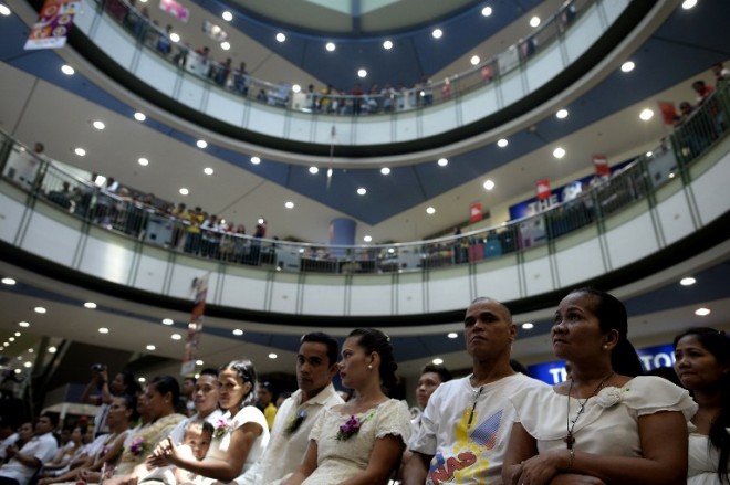 This picture taken on June 21, 2015 shows a mass wedding held inside a shopping center in Manila. With their functions expanding from shopping and dining to venues for Catholic mass, Zumba workouts or even weddings, experts say malls are taking on a more important role at the heart of communities. AFP PHOTO