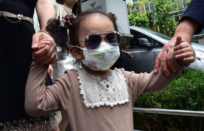 A girl wearing a face mask walks on a street in Seoul on June 23, 2015. South Korea on June 23 reported three new MERS cases but no additional deaths, bringing to 175 the total number of confirmed cases. AFP PHOTO