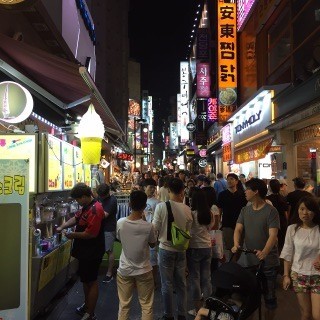 Myeongdong, a famous shopping district in Seoul, is filled with shoppers at night.
