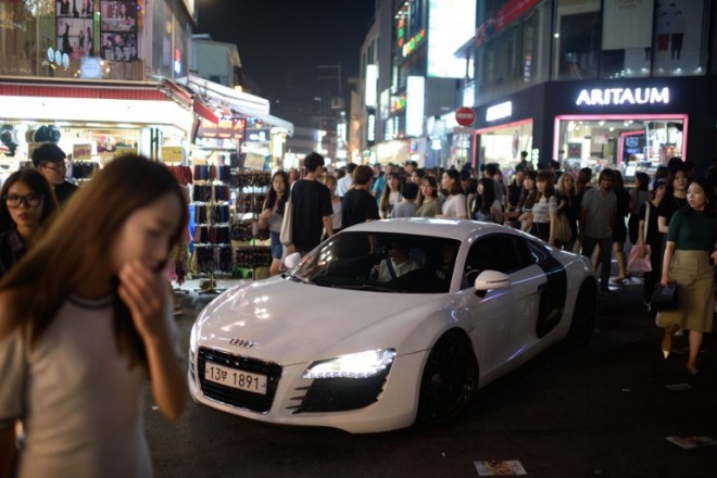 In a photo taken on August 15, 2015 an Audi sports car drives through the popular night spot of Hongdae in Seoul. Seoul is emerging as Asia's new fashion showcase, with the world's top luxury firms seeking to cash in on the regional trend-setting popularity of South Korean pop culture. Fast-growing Asia is a key market driving the global luxury industry, with purchases by Chinese consumers accounting for one third of global sales, according to market researcher Bain & Company. AFP PHOTO / Ed Jones
