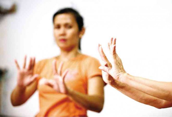 A STUDENT observes as Amilbangsa (right) flexes her fingers and wrists as part of a warm-up session.