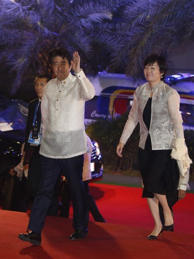 Japan's Prime Minister Shinzo Abe (L) waves as he arrives with wife Akie (R) for a welcome dinner during the Asia-Pacific Economic Cooperation (APEC) summit in the capital city of Manila on November 18, 2015. Asia-Pacific leaders are meeting in Manila for a summit meant to forge trade unity but with the spotlight instead on a tense contest for territory in the South China Sea.   AFP PHOTO / POOL / EDGAR SU