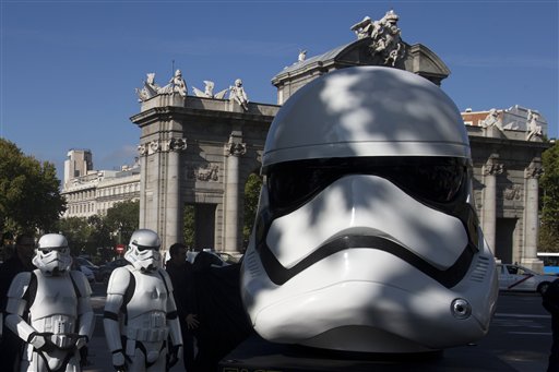 Star Wars Storm Trooper characters stand in front of the Puerta de Alcala monument, by a giant Star Wars helmet that was unveiled during the inauguration of an open air exhibition called 'Face the Force' in Madrid, Spain, Friday, Oct. 30, 2015. Seven other giant helmets are due to be placed in various corners in the city. AP Photo