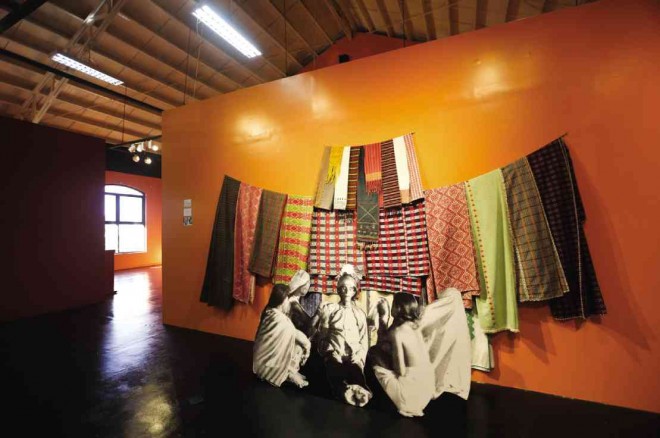 A LIFE-SIZE reproduction of “TheWake of Malakai,” a leader of the Tingguian tribe. Above the figures is a display of blankets, wrap skirts and loincloths that served two purposes: to indicate the great wealth of the deceased and to ward off evil spirits that would have to count each thread of the textiles displayed before they could harm the deceased or his family.